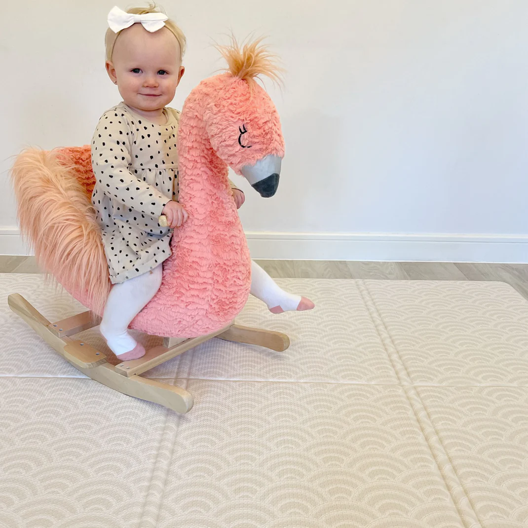 Girl riding a toy horse on a playmat