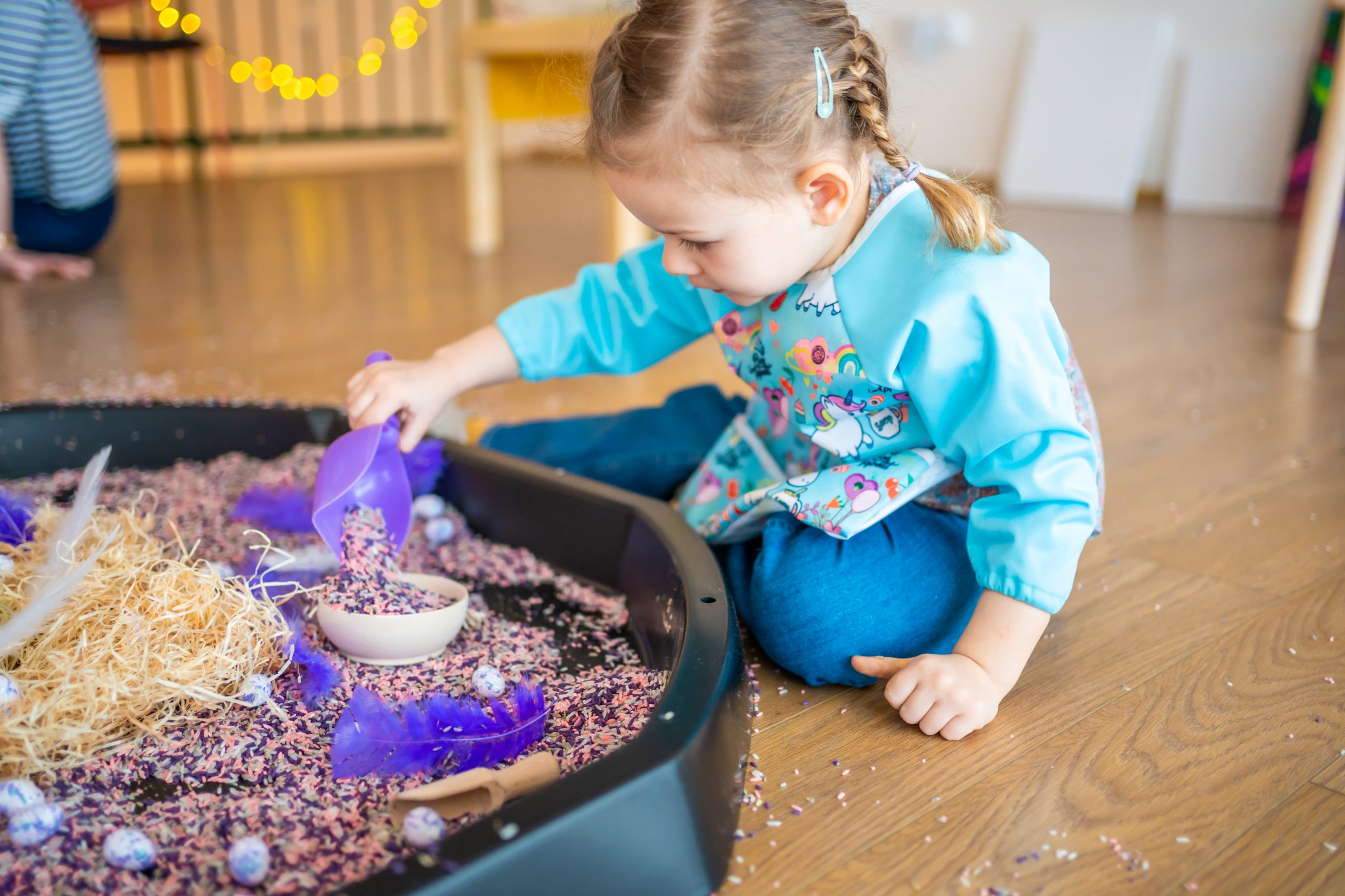 Little girl playing with sensory colorful rice. Sensory development and experiences, themed activities with children, fine motor skills development